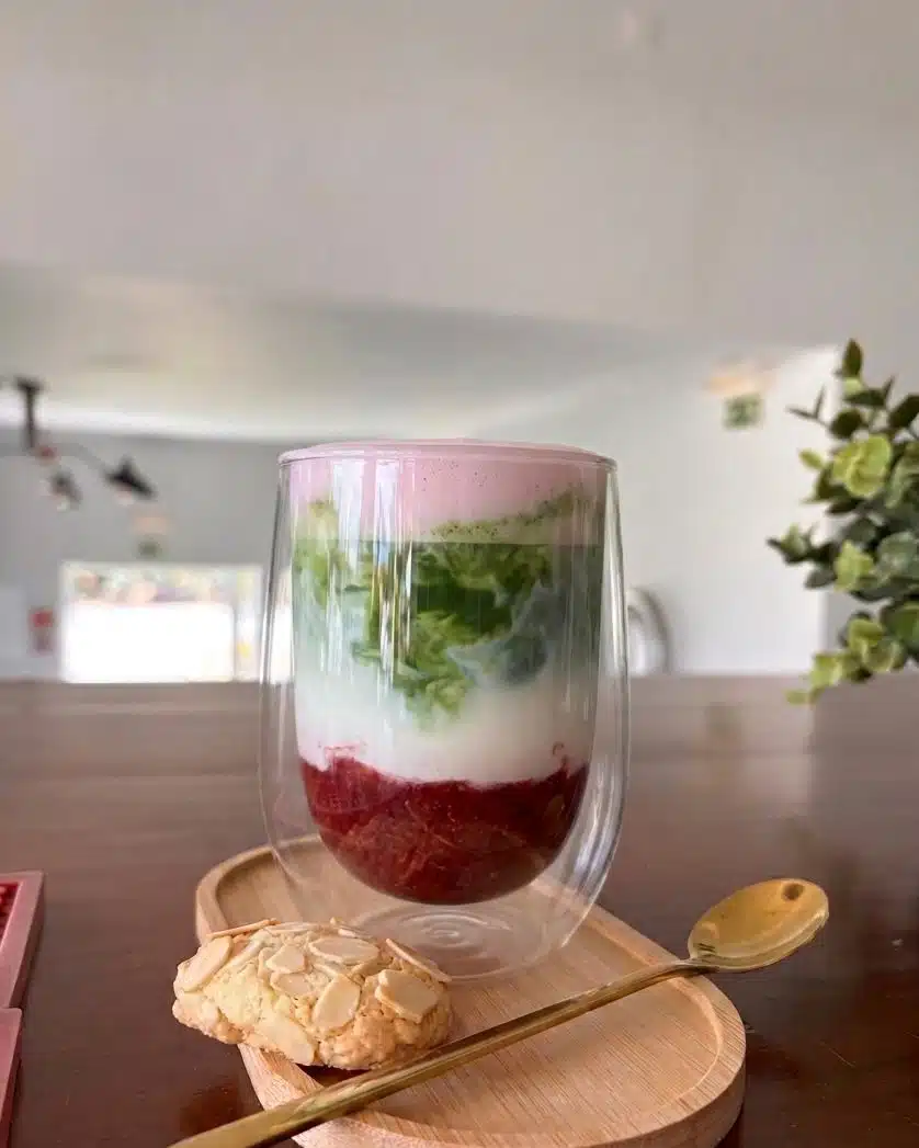 Layered berry and matcha drink with an almond biscuit