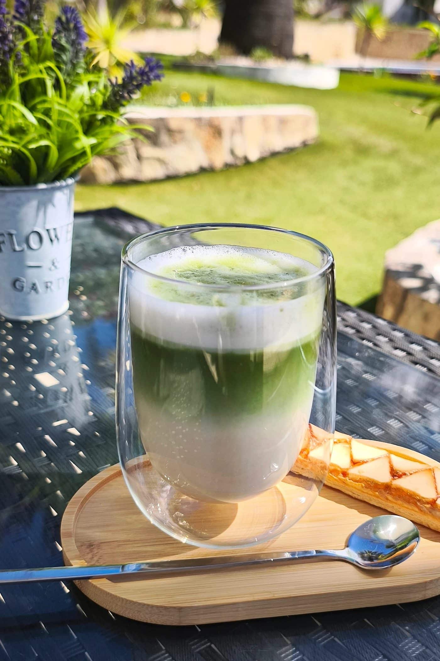 Iced matcha latte with a cream cloud, hand-whisked on a bamboo board