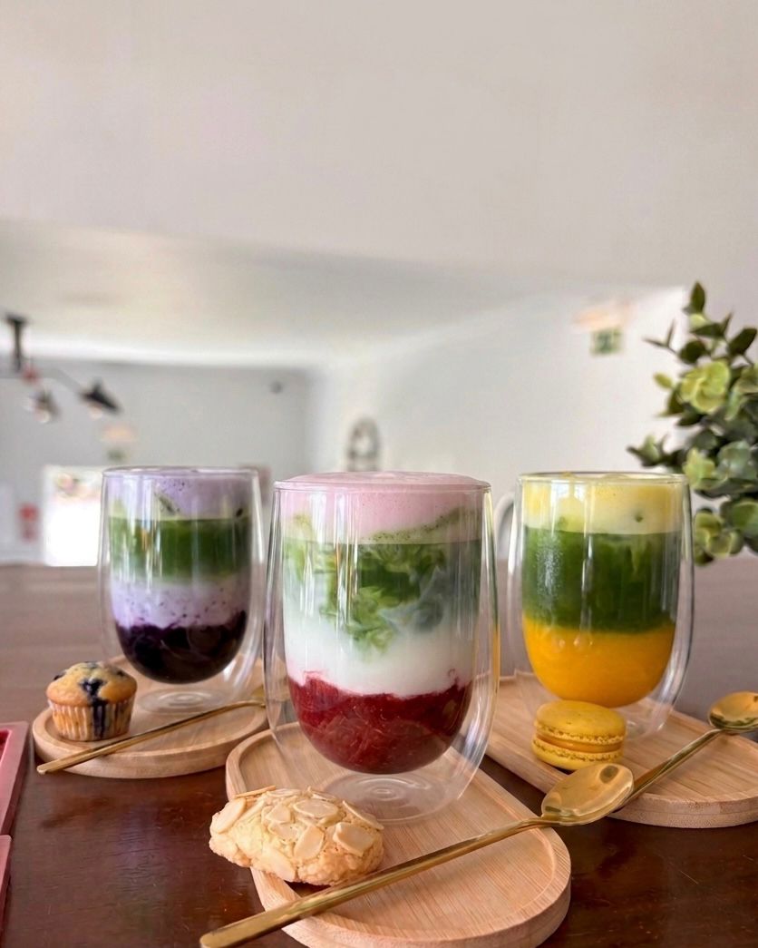 Three layered matcha drinks in glass cups on wooden boards